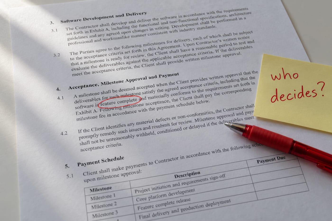 Printed SOW with 'feature complete' circled in red pen and a sticky note asking 'who decides?'