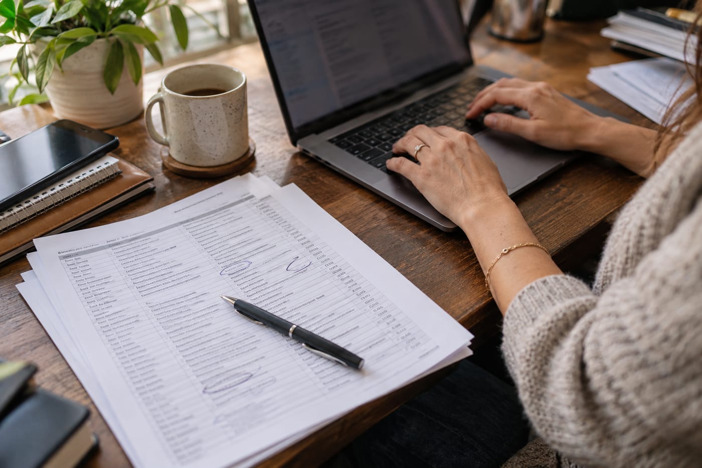 Hands on a keyboard next to a printed spreadsheet of customer email subject lines being reviewed and marked up