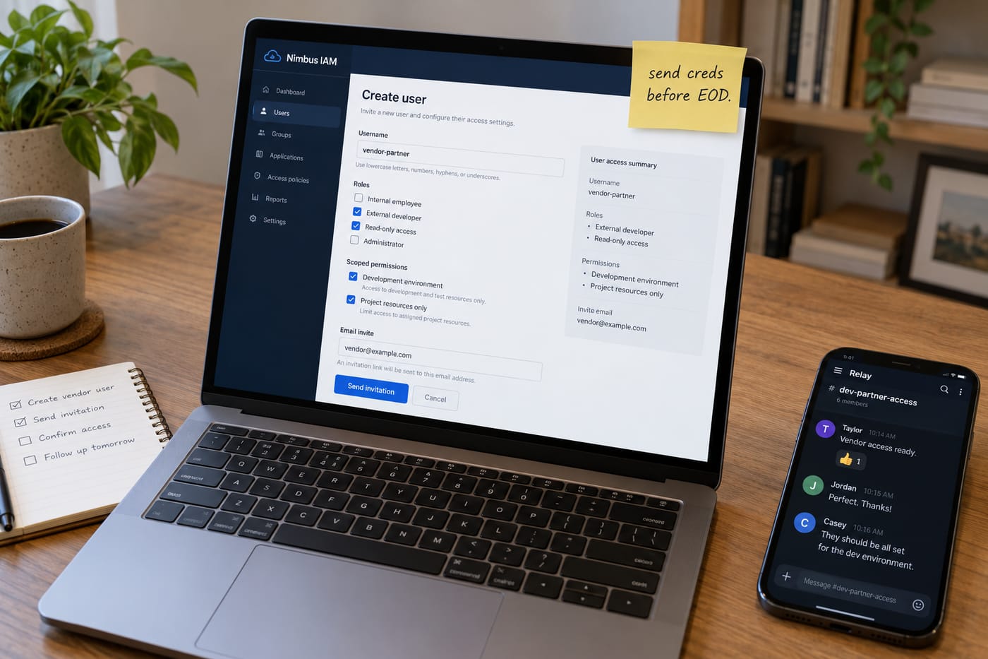 MacBook showing an AWS IAM user-creation screen next to a phone with a Slack access thread, on a home office desk.