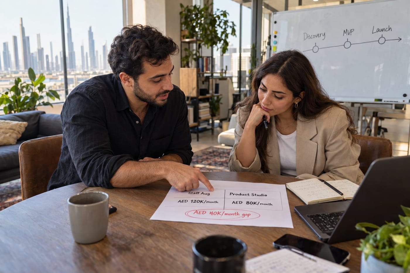 Founder and studio lead lean over a cost-breakdown sheet in a Dubai office, with AED figures and a 40K gap circled in marker.