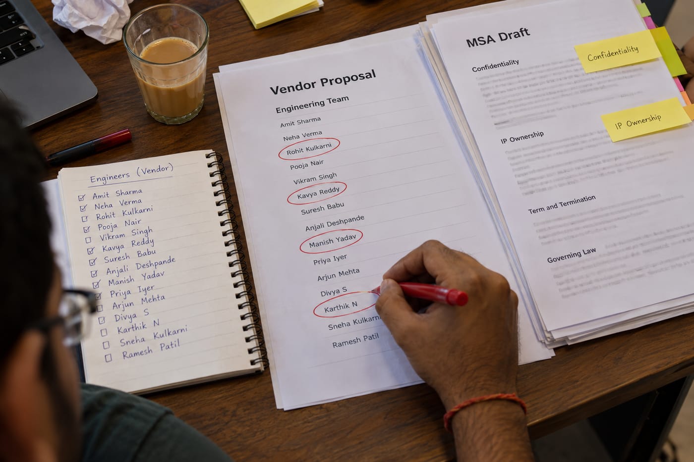Vendor proposal and MSA draft laid out on a desk with engineer names circled in red pen before a vendor review call